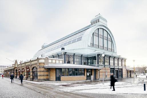 Människor passerar Stora Saluhallen där snö ligger på marken.
