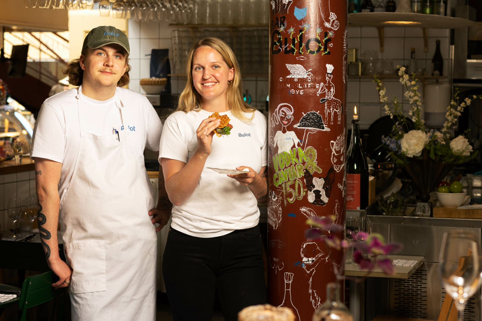 En man och en kvinna står bredvid en stolpe i en restaurang.
