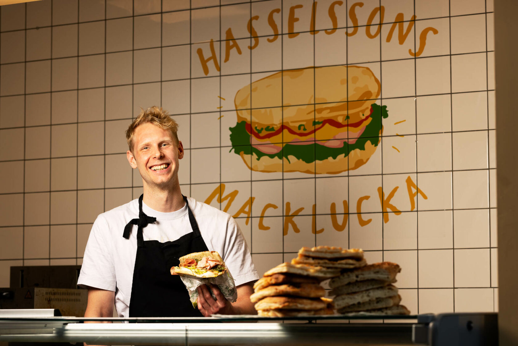 En leende man håller upp en macka.